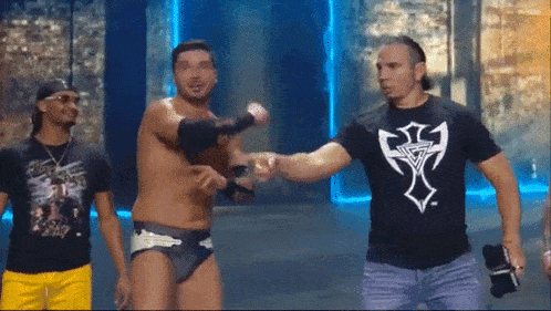 a man wearing a black shirt with a cross on it shakes hands with another man