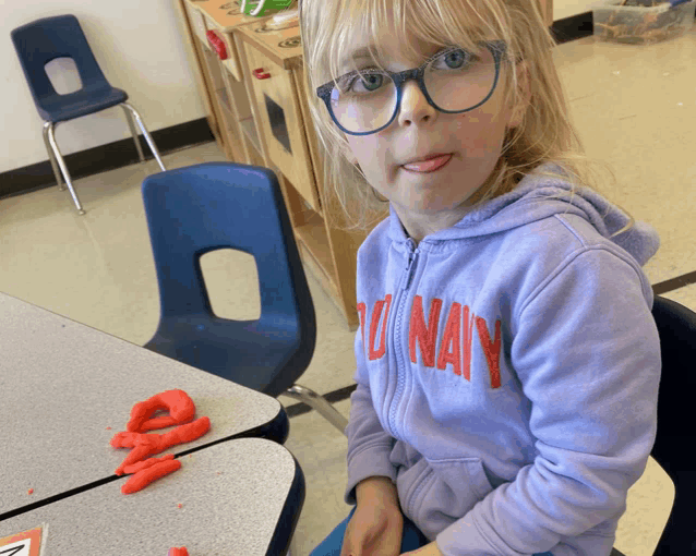 a young girl wearing glasses and a purple sweatshirt that says navy