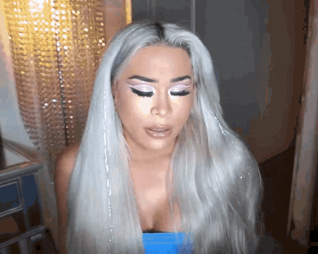 a woman with long white hair is wearing pink eye shadow