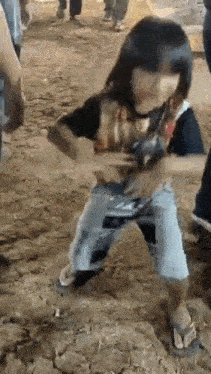 a little girl is standing on a dirt field .