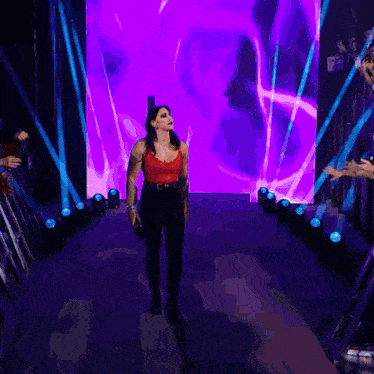 a woman in a red top is walking through a tunnel of purple lights