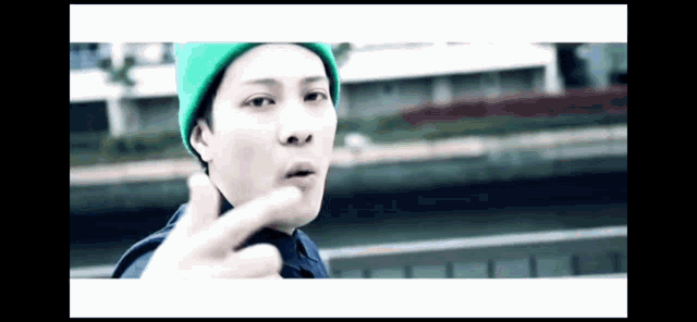 a man wearing a green beanie is giving the middle finger .