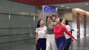 a group of women are laughing in a hallway with a gifrun.com watermark