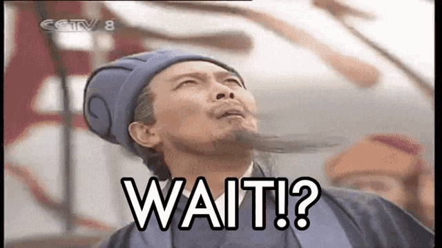 a man with a beard is wearing a blue hat and says wait ?