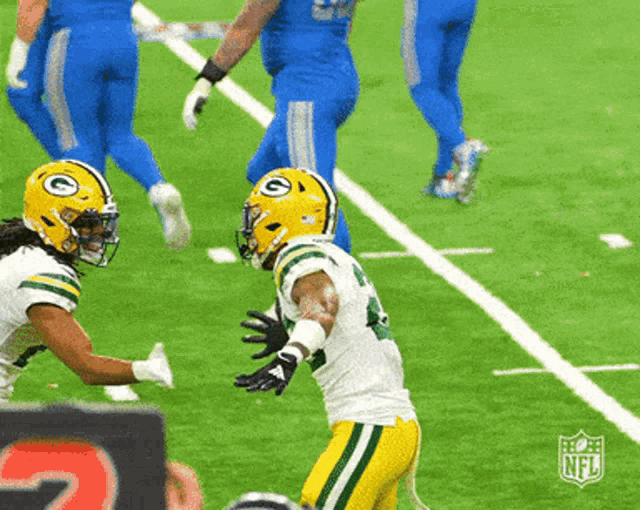 a football player wearing a green bay packers helmet is being tackled by another player