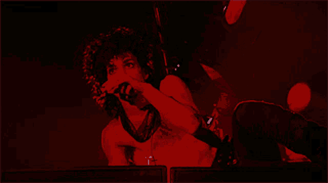 a man is giving the middle finger while singing into a microphone in a dark room