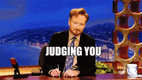 a man in a suit and tie is sitting at a desk with the words judging you written on it
