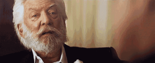 a man with a beard is sitting in a chair and looking at the camera .