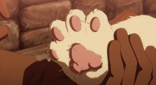 a person is petting a cat 's paw with a brick wall in the background