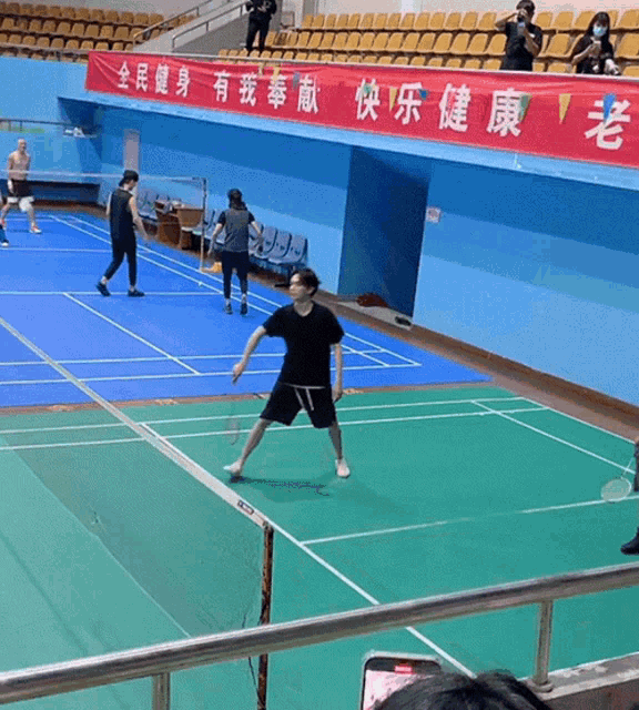 a group of people are playing badminton on a court with a banner that says ' chinese ' on it