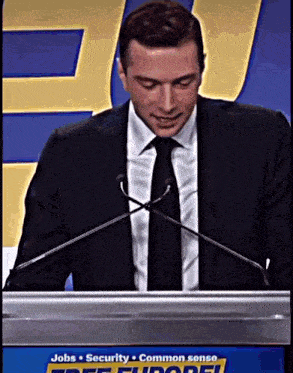 a man in a suit and tie is giving a speech at a podium that says jobs security and common sense