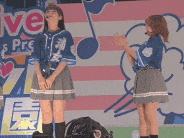 two girls standing on a stage in front of a sign that says live