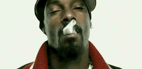 snoop dogg is smoking a cigarette with his eyes closed and smoke coming out of his mouth .