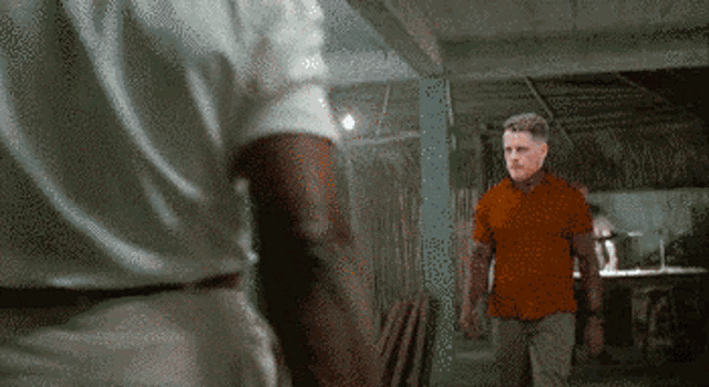 a pixelated image of a man in an orange shirt standing next to another man in a white shirt