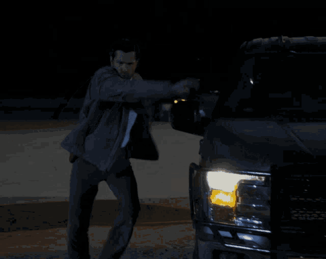 a man in a suit and tie stands in front of a car
