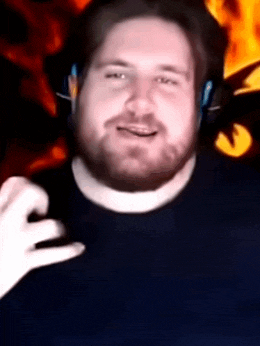 a man with a beard wearing headphones and a blue shirt is smiling .