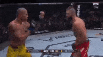 two men are fighting in a boxing ring while a crowd watches .