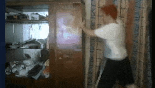 a man in a white shirt is standing in front of a wall with a picture on it