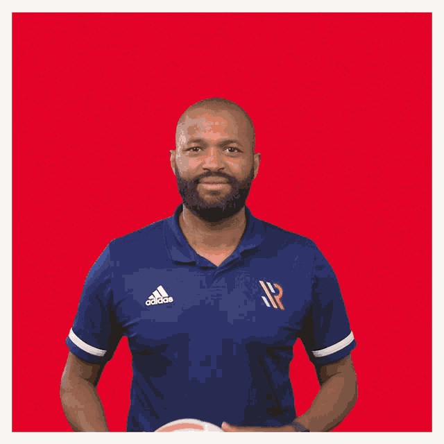 a man in a blue shirt is holding a white volleyball
