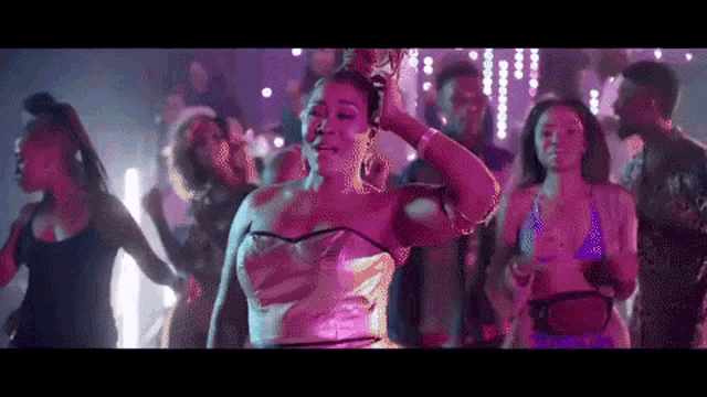 a woman in a gold dress is dancing in a club with a group of people .