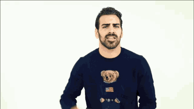 a man wearing a polo bear sweater is making a gesture