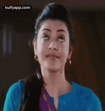 a woman in a blue shirt is making a funny face while looking up .