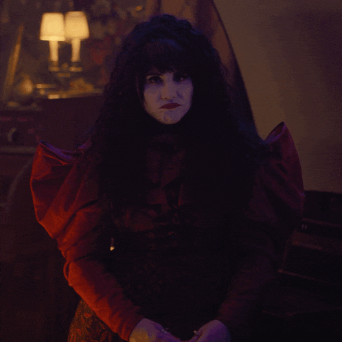 a woman in a red dress stands in the dark