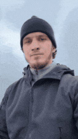 a man wearing a black beanie and a jacket takes a selfie