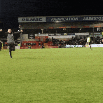 a man is running on a soccer field in front of a sign that says rilmac