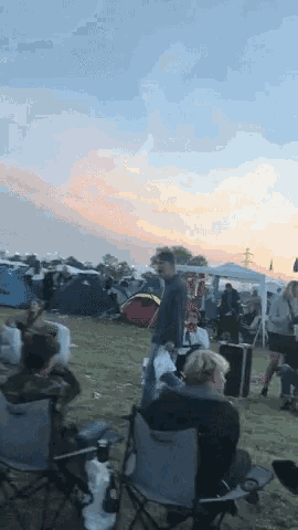 a group of people are gathered in a field with tents