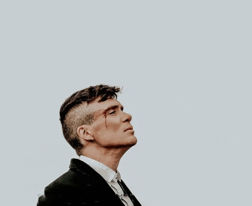 a man in a suit and tie with blood on his face looks up at the sky