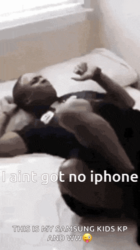 a man is laying on a bed with his legs crossed and says `` i aint got no iphone '' .