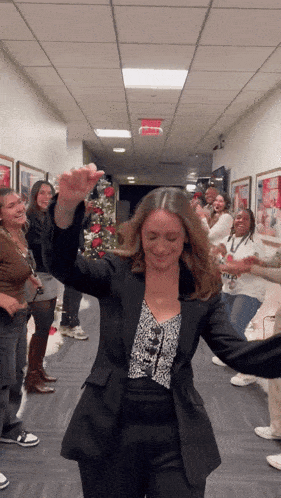 a group of women are dancing in a hallway with a red exit sign above them