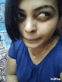 a close up of a woman 's face with a blue shirt and a gold necklace .