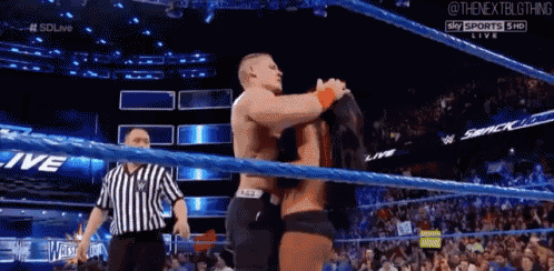 a man and a woman are hugging in a wrestling ring while a referee stands behind them