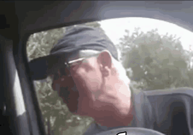 a man wearing a hat and glasses is sitting in a car .