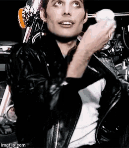 a man wearing a black leather jacket is holding a white ball in his hand .