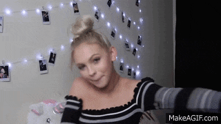 a girl is taking a selfie in front of a wall with pictures on it