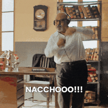 a man wearing headphones is dancing in an office with the words nacchooo written on the bottom