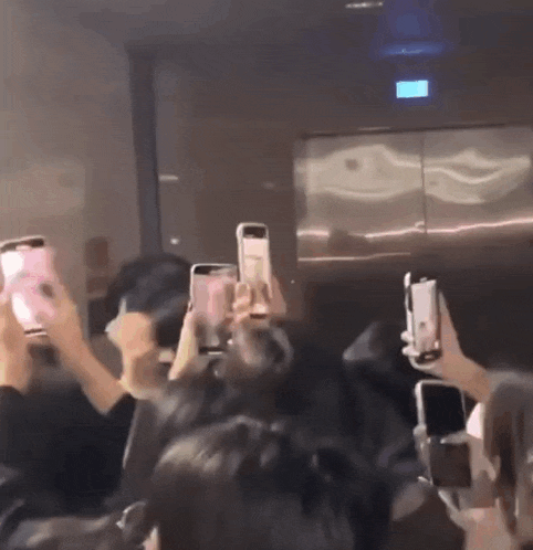 a group of people are holding up their cell phones
