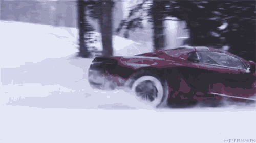 a red sports car is driving in the snow .