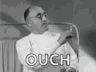 a black and white photo of a man in a lab coat holding a syringe and the word ouch .