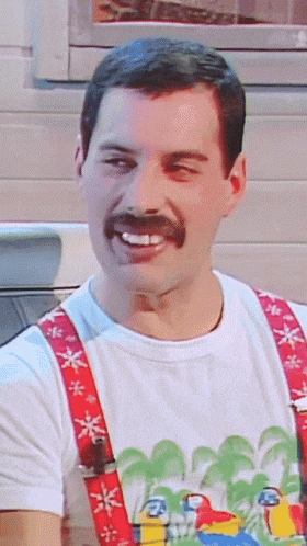 a man with a mustache and suspenders smiles