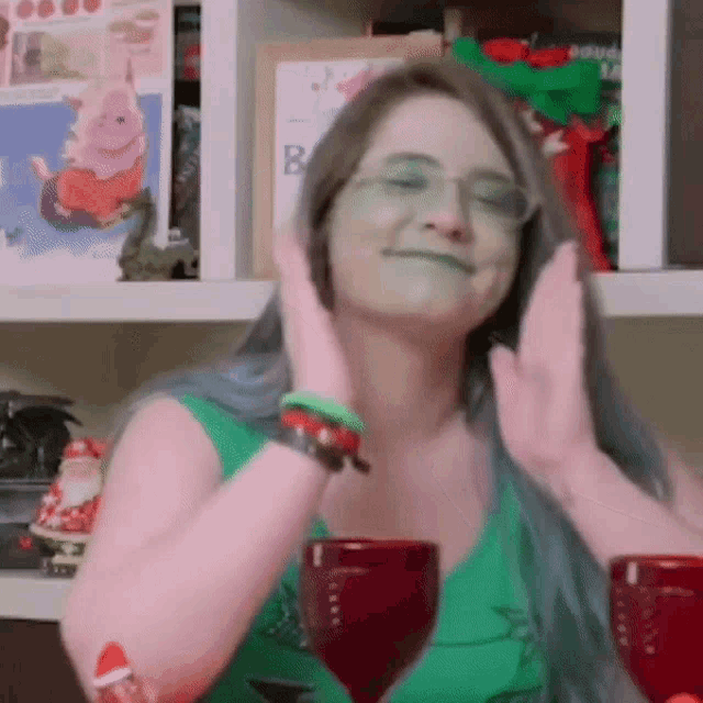 a woman wearing glasses and a green top is sitting at a table