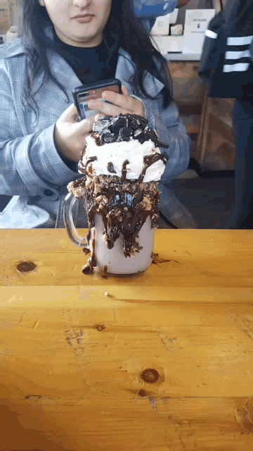 a woman sitting at a table with a milkshake on it