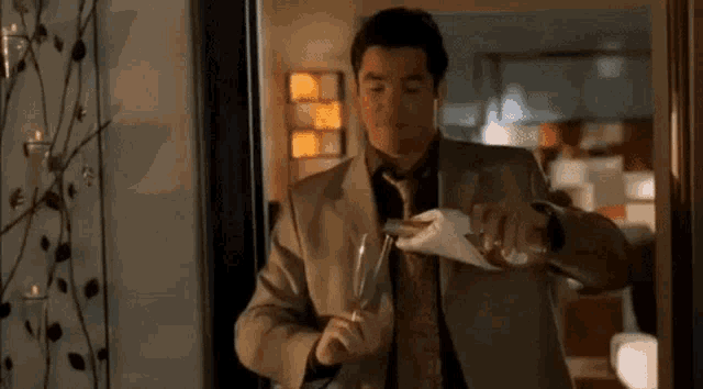 a man in a suit and tie is pouring a drink into a glass .