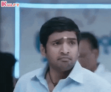 a man in a blue shirt is making a funny face while standing in front of a crowd .