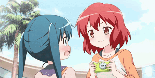 a girl with red hair is holding a camera and talking to another girl