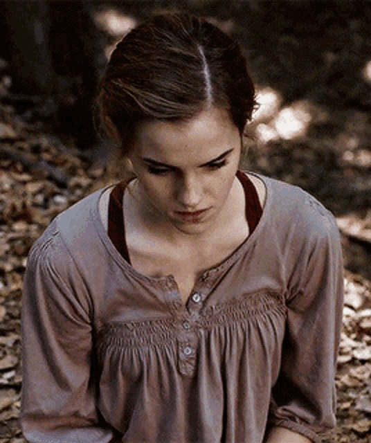a woman in a brown shirt is sitting on the ground