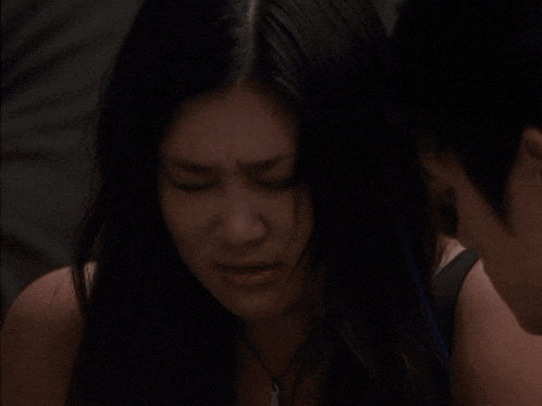 a woman with a necklace around her neck looks at a man